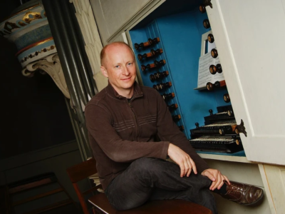 James Johnstone sat on a stool in front of harpsichord